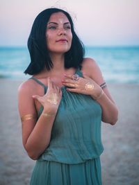 Thoughtful young woman with flash tattoo standing at beach