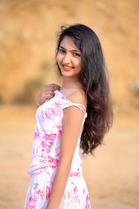 Side view portrait of smiling young woman standing on field