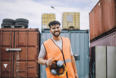 Portrait of happy young construction worker with hardhat at site
