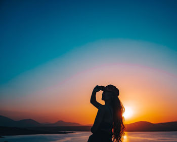 Silhouette woman standing against sea during sunset