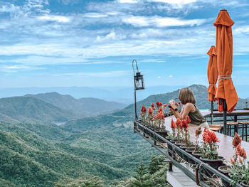 People on railing by mountain against sky