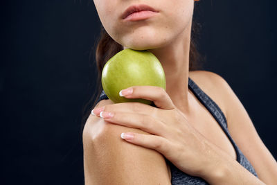 Midsection of woman holding apple against black background