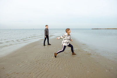Full length of people on beach against sky