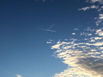 Low angle view of vapor trails against blue sky