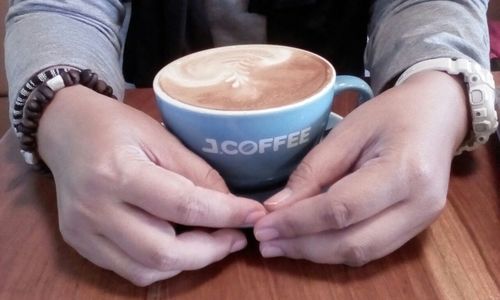 Midsection of man holding coffee cup