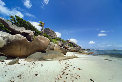 Rocks on beach against blue sky