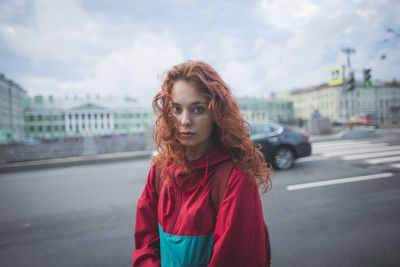 Portrait of young woman standing on road in city