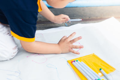 High angle view of baby hand holding paper on table