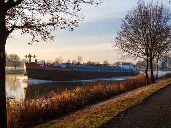 Road by river against sky at sunset