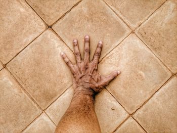 Cropped image of hand on tiled floor