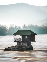 Built structure by lake and mountain against sky