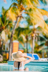 Rear view of woman in swimming pool against trees