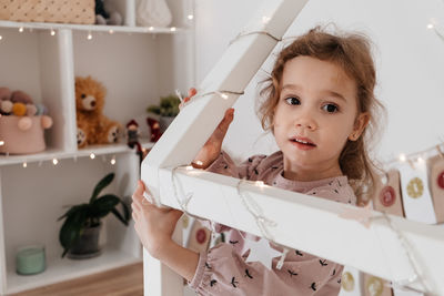 Toddler child gets new advent calendar task, waiting for christmas. festive mood for cute curly girl