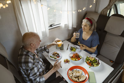 Senior couple eating lunch while talking together in motor home
