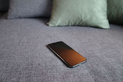 Close-up of mobile phone on bed at home