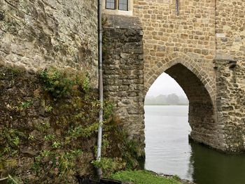 Arch bridge over river against wall