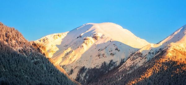 Scenic view of snowcapped mountains against clear blue sky