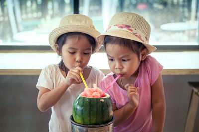 Close-up of twin sisters having drink in restaurant