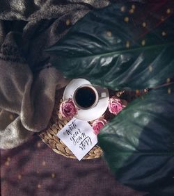 High angle view of hand holding coffee cup on bed