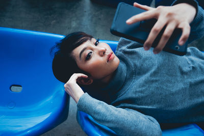 High angle view of young woman taking selfie with mobile phone while lying on chair
