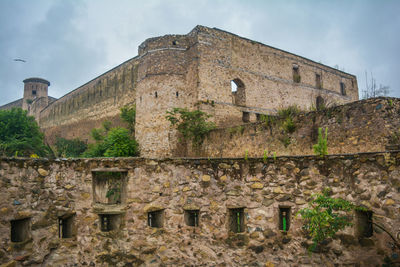 Low angle view of old ruin building against cloudy sky