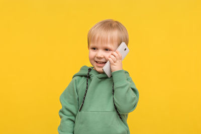 Portrait of smiling boy against yellow background