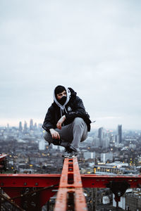 Man standing by building against sky in city