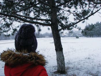 Rear view of woman walking on snow covered tree