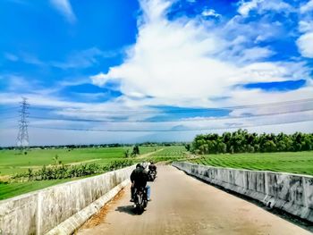 Rear view of man riding bicycle on road