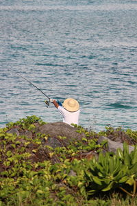 Rear view of man fishing in sea