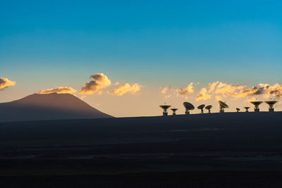 Silhouette birds on landscape against sky during sunset