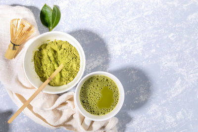 Matcha green tea cup and matcha tea powder bowl, napkin on grey. top view, shadows, copy space.