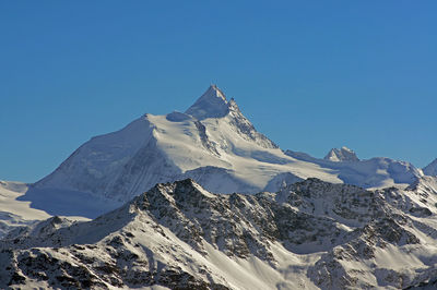 Low angle view of snowcapped mountain against clear sky