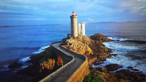 Lighthouse by sea against sky