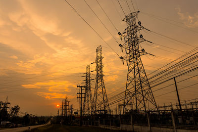 Low angle view of silhouette electricity pylon against sky during sunset