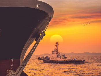 Boat sailing on sea against orange sky