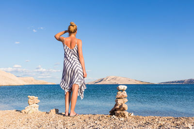 Man standing at beach against clear blue sky