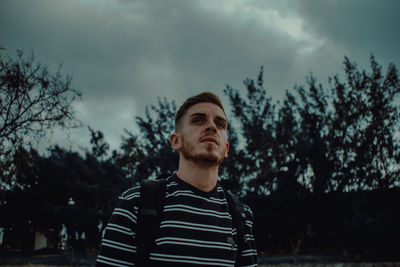 Portrait of young man looking away against sky