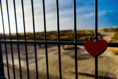 Close-up of padlocks on railing against fence