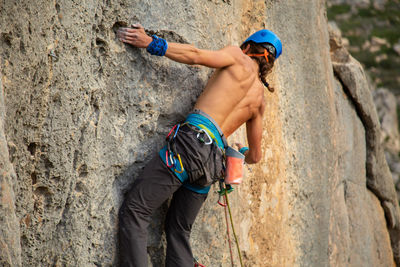 Low angle view of shirtless man rock climbing 
