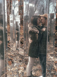 Woman standing by window in forest