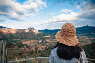 Rear view of woman standing by railing against sky