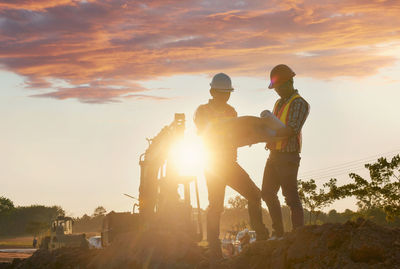 Rear view of man standing against sky during sunset