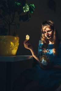 Girl holding potato chip sitting at home