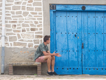 Full length of young man relaxing on seat by house