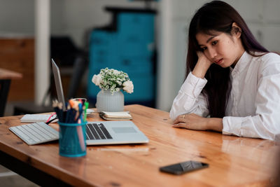 Woman using mobile phone while sitting on table