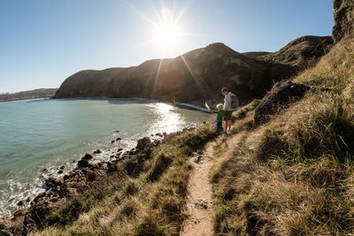 Father and son looking down at ocean from mountain path