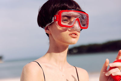 Portrait of young woman wearing sunglasses against sea
