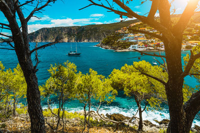 Scenic view of sea by trees against sky