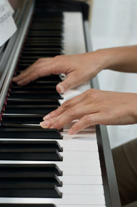 Cropped hands of woman playing piano